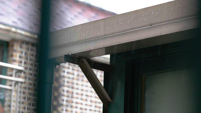 Drizzle on a metal roof of a building during a rainy day