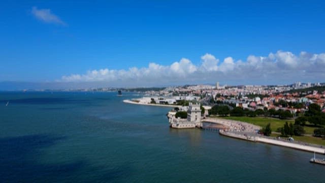 Clear Day View of Belém Tower by the Water with Tourists