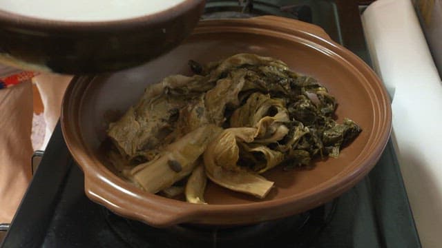 Pouring broth into a pot containing fermented kimchi