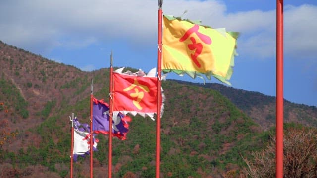 Colorful traditional flags fluttering on poles against a backdrop of green hills and blue sky