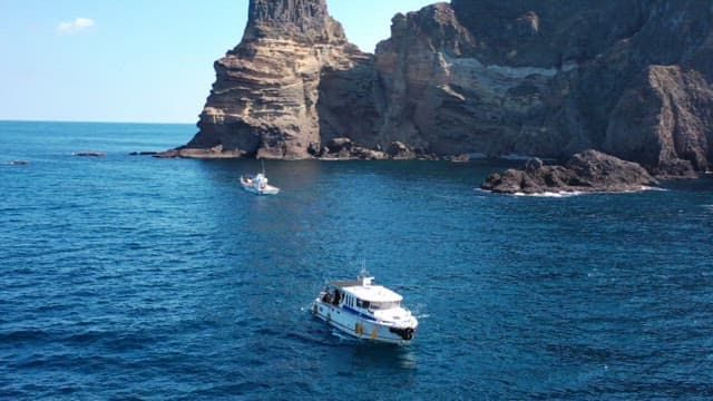 Boats Navigating Near Majestic Cliffside