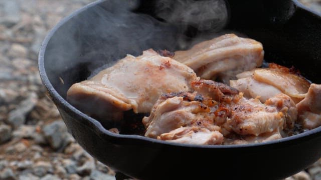Pouring wine over chicken cooking in an oiled frying pan