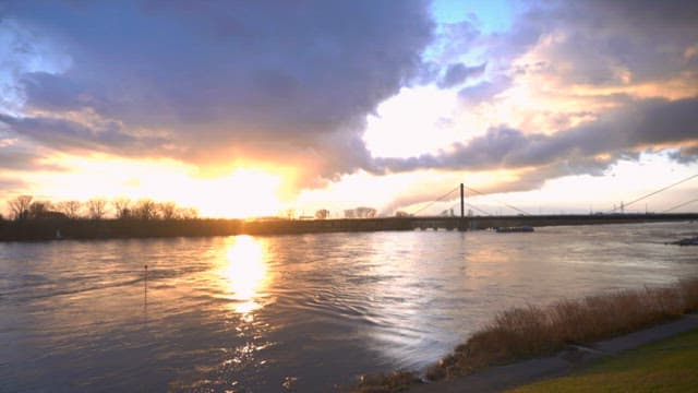 Boat passing on a quiet river under a sunset sky
