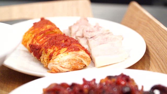 Korean food on the table with napa wraps with pork and grilled webfoot octopus