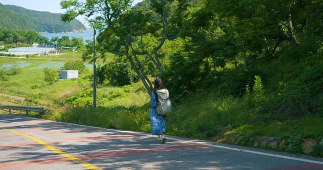 Woman Walking on a Countryside Road with Backpack
