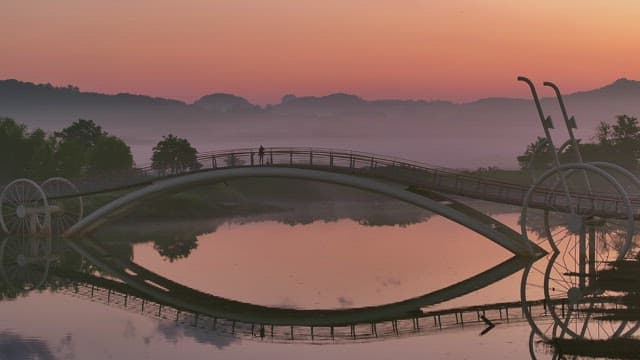 Serene bridge over a misty river at sunset