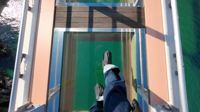 Tourists Walking Across a Glass Bridge over the River on a Sunny Day