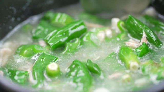 Soup with fresh green peppers being stirred into the soup