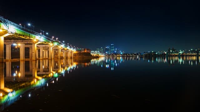Illuminated Cityscape Reflecting on Calm River at Night