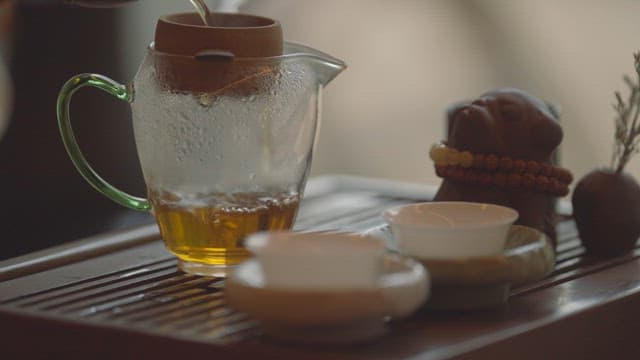 Hand pouring warm tea to a tea cup