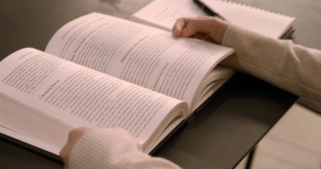 Person Reading an Open Book in Cozy Atmosphere