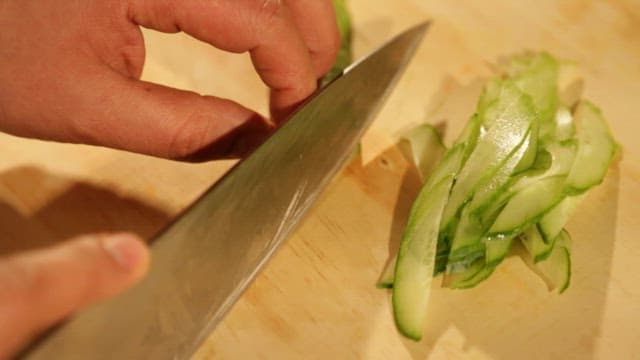Skillfully Slicing a Cucumber in Wooden Cutting Board