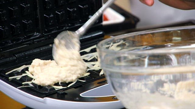 Potato batter being spread on a waffle maker