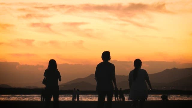 People Walking on the Beach Under a Beautiful Sky at sunset