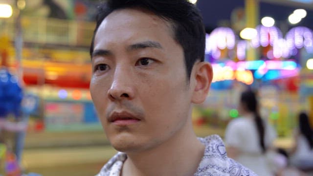 Man in a colorful amusement park at night