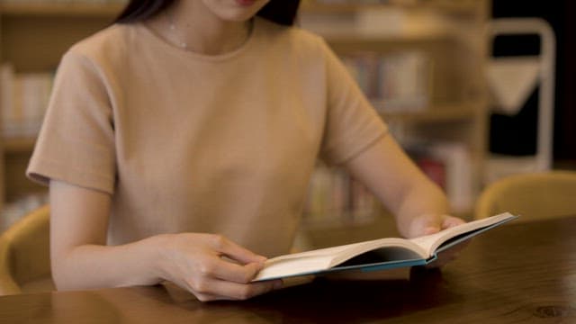 Young Woman Reading Book in Library