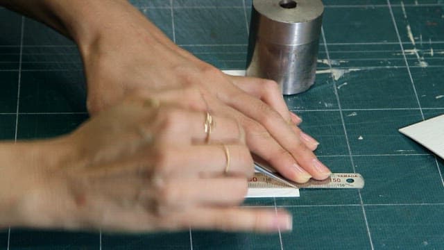 Hands cutting paper precisely on a green grid cutting mat