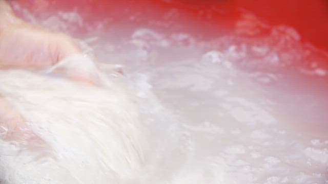 Hands washing noodles in cold water