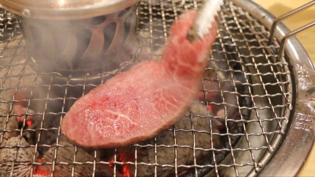 Grilling juicy beef steak over charcoal flames