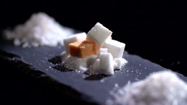 White sugar cubes and salt stacked on a dark surface