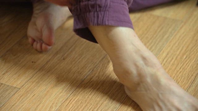 Elderly Man Rolling Up His Pants and Massaging Legs