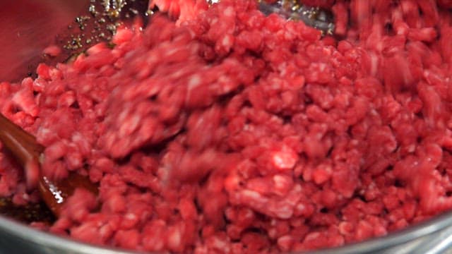 Mixing minced beef in a metal bowl