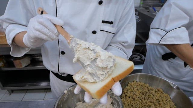 Chef spreading cream on bread slice