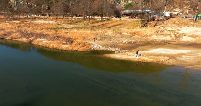 Person Walking by a Riverside in Nature
