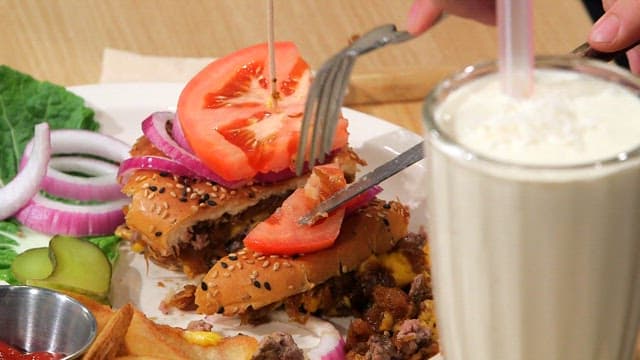 Bite of juicy burger with a milkshake