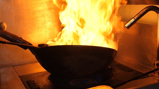 Chef Cooking Webfoot Octopus with a Wok in a Restaurant Kitchen