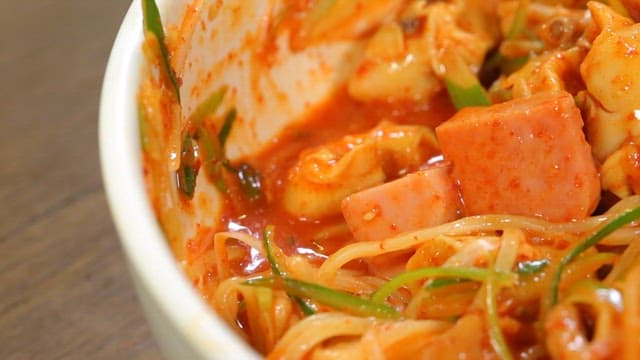 Jjolmyeon with ham and green onion mixed in a bowl