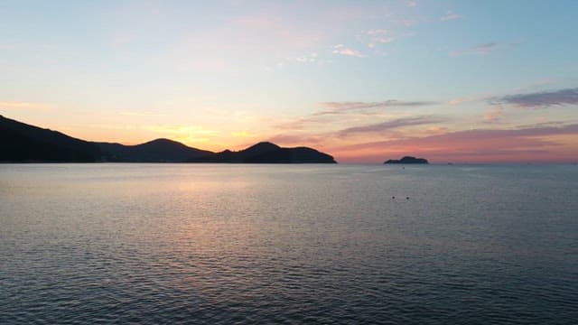 Sunset Over a Calm Seaside with Silhauette of Island