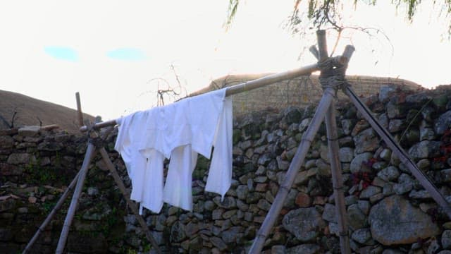 Stone wall with clothes drying in the morning sun in thatched-roof village