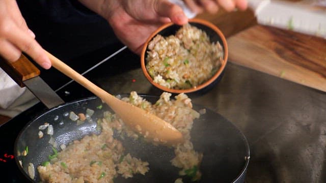 Stir-fried rice being served in a bowl