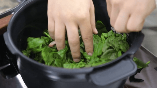 Putting fresh spinach in a rice cooker