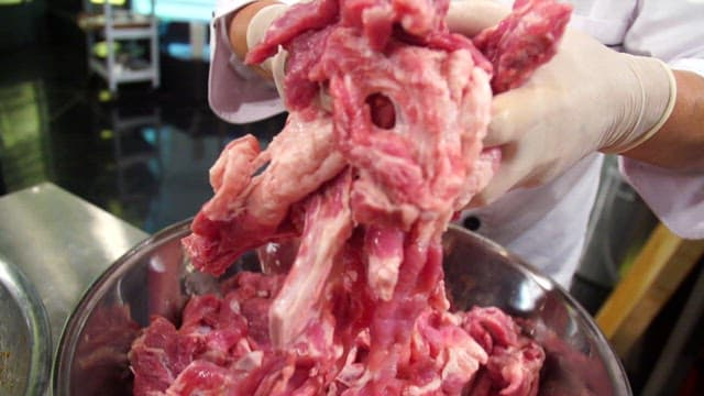 Chef preparing raw meat in a bowl with onions and soy sauce seasoning