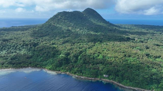 Lush rainforest and mountains with cabins visible on a sunny day