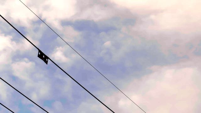 Power lines stretching across a sky filled with clouds.