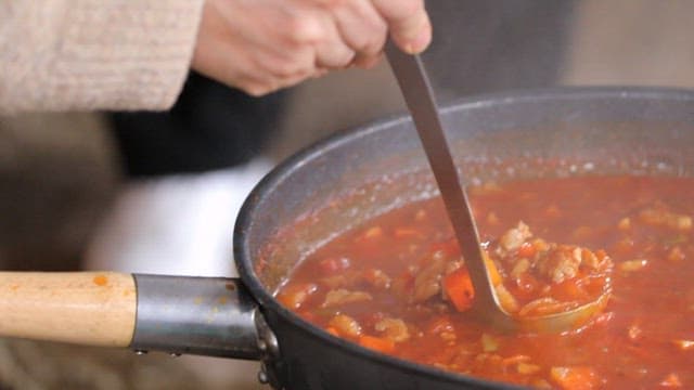 Ladle serving stew into a bowl