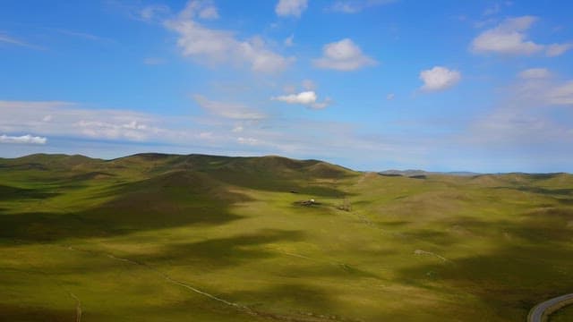 Vast green hills under a clear blue sky