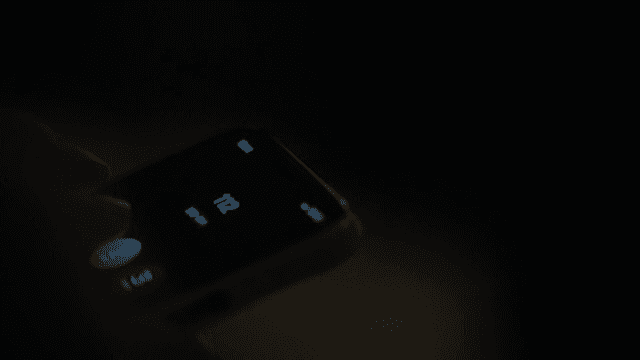 Woman Pressing 211 on Cell Phone Keypad in Dark Room