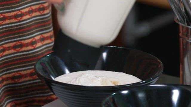 Cold Soybean Soup Being Poured into a Black Bowl with Noodles