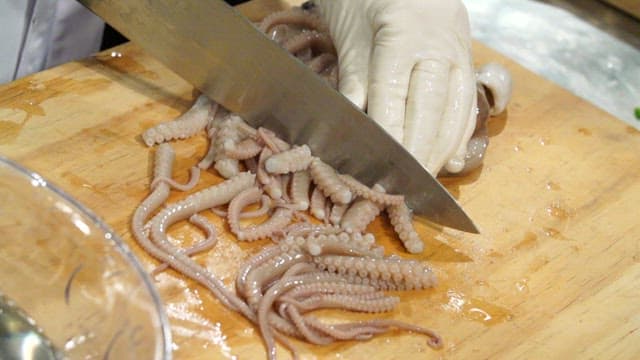 Cutting fresh octopus on a wooden board