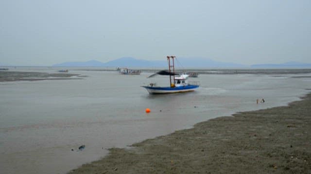 Fishing boats passing near the coastal mudflats where the tide comes in