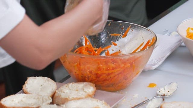 Placing Seasoned Carrots on Top of a Baguette Covered in Cream Cheese