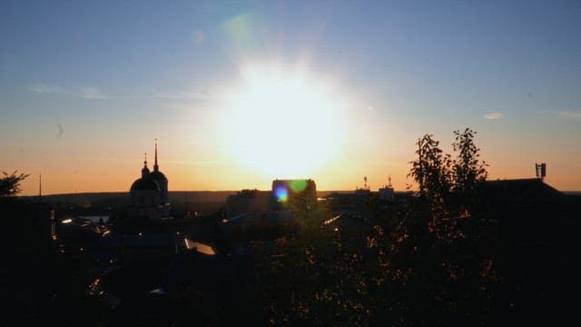 Sunset over a city with rooftops and church silhouettes