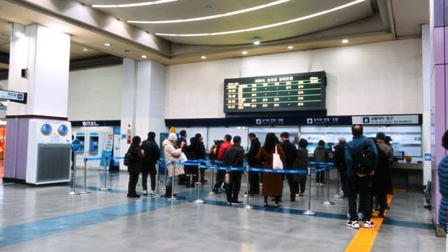 Commuters lining up at a train station ticket counter