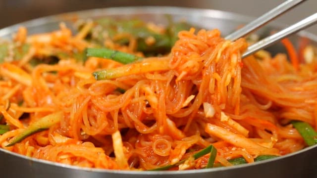 Chopstickful of delicious bibim jjolmyeon with fresh vegetables