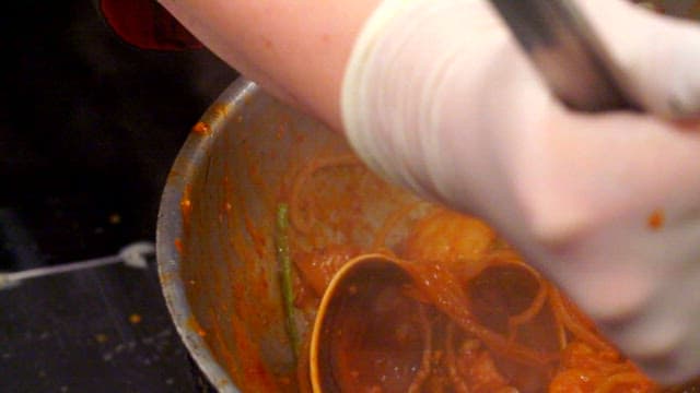 Braised spicy seafood with bean sprouts, abalone and squid being stirred in a pot
