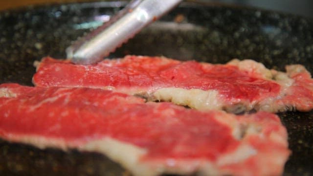 Sizzling beef slices on a hot pan